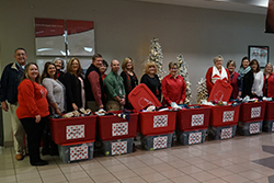 A group of school officials and Enrichment staff with tote containers filled with hats and gloves.