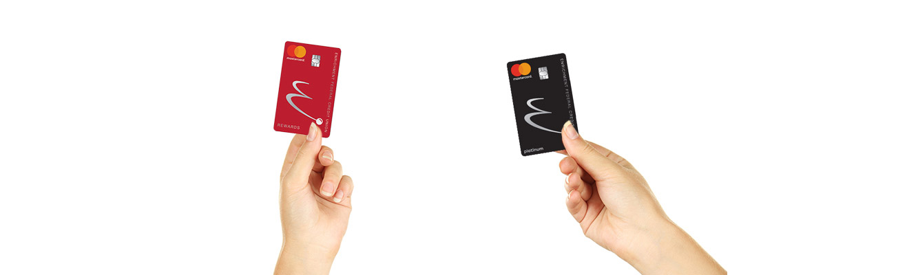 Two hands holding two different Enrichment credit cards. 